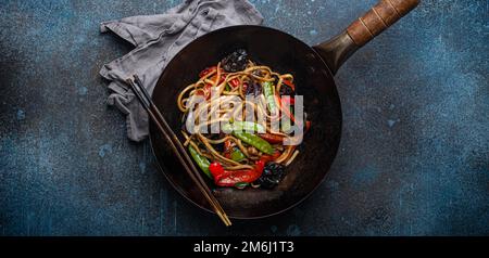 Asiatische rühren braten Nudeln mit Gemüse in schwarzen Wok Pfanne Stockfoto