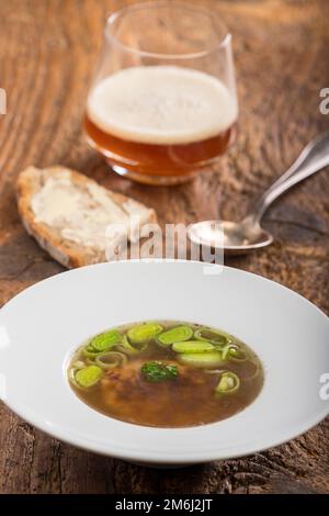 Österreichische Käseklößchen-Suppe auf Holz Stockfoto