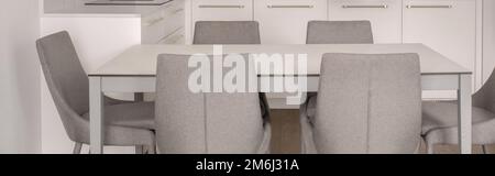 Warme weiße Kücheneinrichtung, graue Stühle, Eichenfußboden. Modernes Küchenkonzept Stockfoto