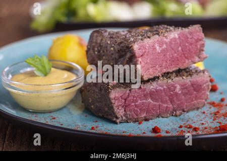 Steak-Scheiben auf blauem Teller Stockfoto