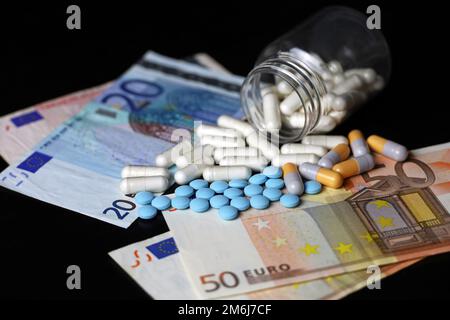 Pillen auf Euro-Banknoten, Medikamente in Kapseln, die aus der Flasche verstreut sind. Gesundheitskonzept, Pharmaindustrie, Arzneimittelpreise in der EU Stockfoto