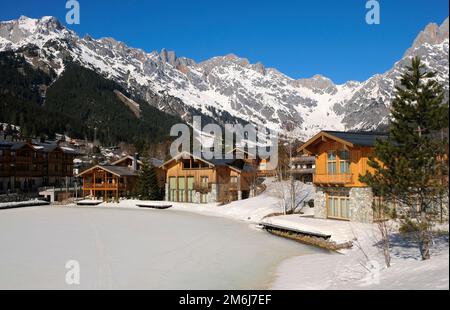 Berghütten neben einem gefrorenen Eissee im Winter Stockfoto