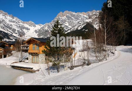 Berghütten neben einem gefrorenen Eissee im Winter Stockfoto