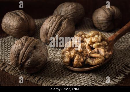 Walnüsse und Kerne in einem Korb auf dunklem Holzhintergrund Stockfoto