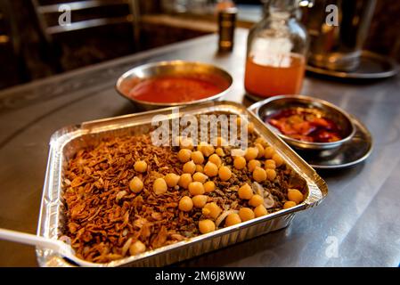 Koshary, Kushari oder Koshari das beliebteste kulinarische Gericht in Ägypten, eine Mischung aus Nudeln, Reis, Linsen, Kichererbsen und gebratenen Zwiebeln, garniert mit Tomaten Stockfoto