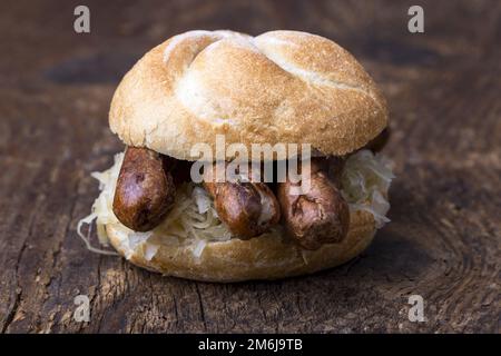 Nürnberger Würstchen mit Sauerkraut in einer Rolle Stockfoto