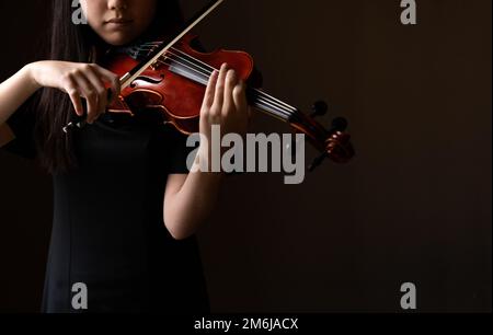 Teenager, die in formeller Kleidung Geige spielen Stockfoto