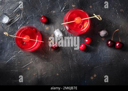 Cocktailkirsche und ein Mocktail auf dunklem Hintergrund, ein lebhaftes rotes Getränk Stockfoto