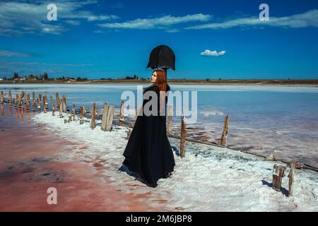 Eine Frau in schwarzer Kleidung auf einem rosa See Stockfoto