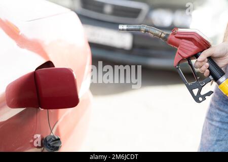 Ein Mann mit Füllpistole in der Hand an der Tankstelle Stockfoto