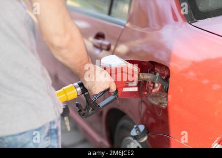 Ein Mann mit Füllpistole in der Hand an der Tankstelle Stockfoto