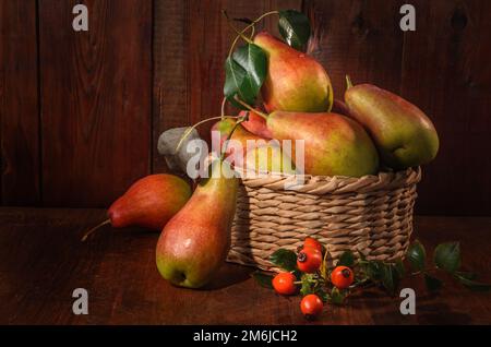 Reife Birnen in einem Korb auf dunklem Holzhintergrund in rustikalem Stil Stockfoto