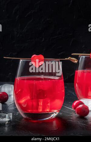 Cocktailkirsche und ein Mocktail auf dunklem Hintergrund, ein lebhaftes rotes Getränk Stockfoto