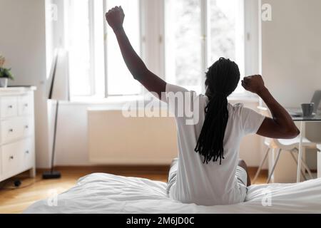 Rückansicht Eines Afroamerikanischen Mannes, Der Sich Morgens Im Bett Ausstreckt Stockfoto