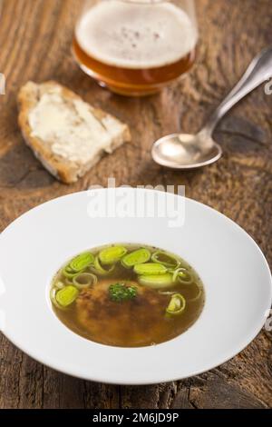 Österreichische Käseklößchen-Suppe auf Holz Stockfoto