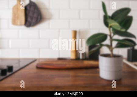 Küchenutensilien aus Messing, Küchenzubehör - verschwommener Küchenhintergrund. Hängende Küche mit weißen Fliesen an der Wand und Holztisch. Stockfoto