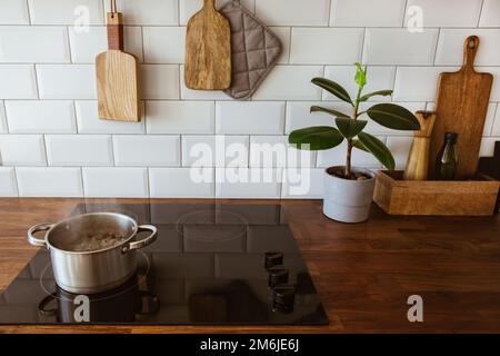 Kochendes Wasser in einem Kochtopf und eine Pfanne auf einem Induktionsherd in der modernen weißen Küche Stockfoto