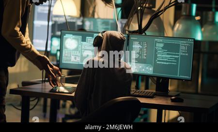 Eine Diebin, die ihr Wissen über Netzwerksysteme nutzt, um auf Daten zuzugreifen und Passwörter zu stehlen. Kriminelle brechen die Firewall für Cyberspionage, Hacktivismus, Kryptojacking. Handgeführte Aufnahme. Stockfoto