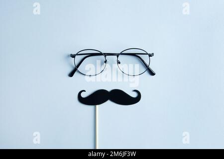 Vatertag-Feiertagskonzept. Transparente Brille, eleganter schwarzer Fotokabinett mit Bart auf blauem Hintergrund. Stockfoto