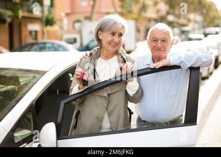 Ein älteres Paar, das neben dem Auto steht Stockfoto