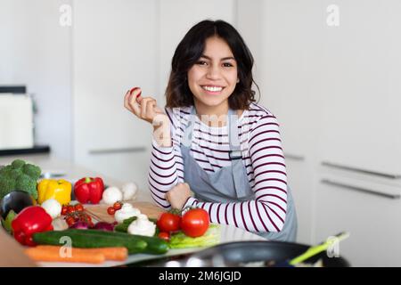 Positive attraktive junge Frau Koch posiert in der gemütlichen Küche Stockfoto