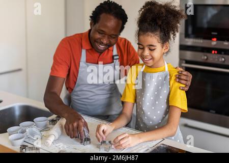 Glücklicher Schwarzer Vater Und Tochter, Die Verschiedene Keksformen Aus Teig Schneiden Stockfoto