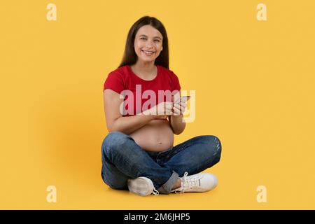 Schöne App. Porträt Einer Schönen Jungen Schwangeren Frau Mit Smartphone In Der Hand Stockfoto