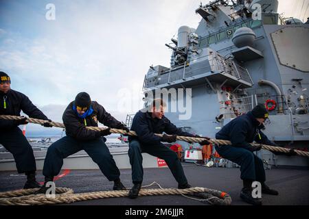 Kiel, Deutschland. 11. Dezember 2022. USA Marinesoldaten, die dem Arleigh-Burke-Klasse-Guided-Missile-Zerstörer USS Paul Ignatius (DDG 117) zugeteilt wurden, legen sich um eine Linie, wenn das Schiff in Kiel ankommt, um einen planmäßigen Hafenbesuch am 8. Dezember 2022. Paul Ignatius, der nach Rota, Spanien, geschickt wird, befindet sich in einem geplanten Einsatz in den USA Marinestreitkräfte Europa Einsatzgebiet, angestellt von den USA Sechste Flotte, um die Interessen der USA, Verbündeten und Partner zu verteidigen. Kredit: Aaron Lau/USA Navy/ZUMA Press Wire Service/ZUMAPRESS.com/Alamy Live News Stockfoto