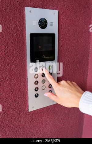 Eine junge Frau wählt den Wohnungscode auf dem Bedienfeld einer elektronischen Gegensprechanlage. Schutz- und Sicherheitskonzept Stockfoto