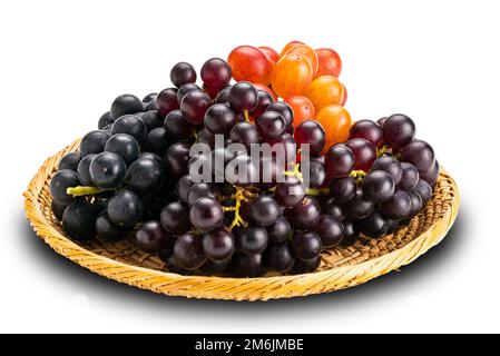 Bündel reifer roter Trauben, schwarzer Trauben und violetter Trauben auf Bambusplatte. Stockfoto