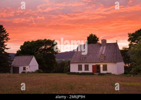 Altes Haus im Stil eines französischen Regimes aus dem Jahr 1752, beleuchtet in der Abenddämmerung im Sommer, Saint-Francois, Ile d'Orleans, Quebec, Kanada. Stockfoto