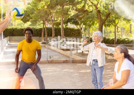 Fröhliche multirassische Gruppe von erwachsenen Menschen spielen Volleyball-Spiel im Freien Stockfoto