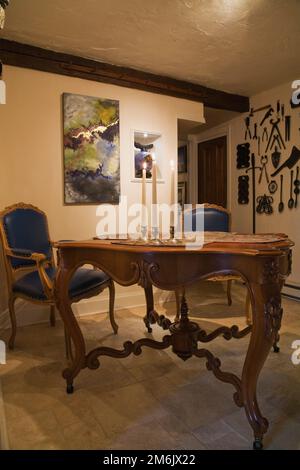 Antiker hölzerner Frühstückstisch und blaue Leder gepolsterte Stühle mit hoher Rückenlehne in der Küche in einem alten Haus im 1809 Cottage Stil. Stockfoto