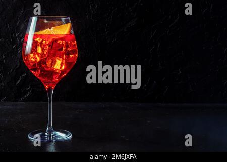 Aperol-Cocktail mit einer orangefarbenen Scheibe, Seitenansicht auf dunklem Hintergrund Stockfoto