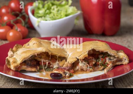 Pizza Calzone auf einem roten Teller Stockfoto