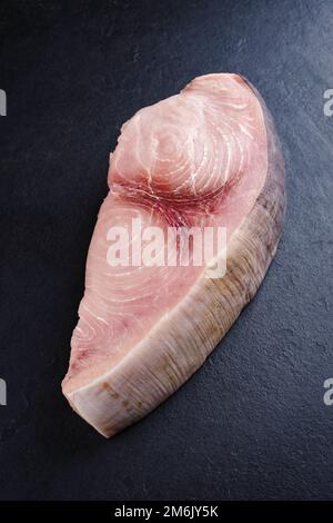 Rohes Schwertfischsteak wird als Nahaufnahme auf einem schwarzen Brett mit Kopierbereich angeboten Stockfoto