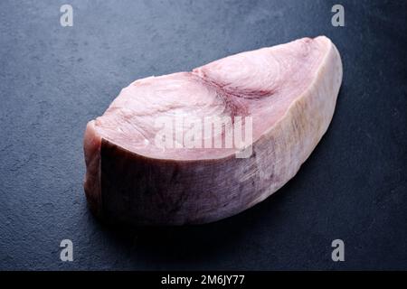 Rohes Schwertfischsteak wird als Nahaufnahme auf einem schwarzen Brett mit Kopierbereich angeboten Stockfoto