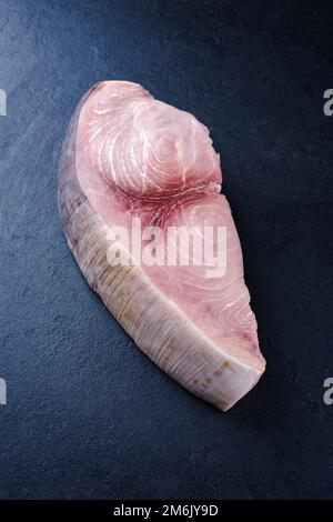 Rohes Schwertfischsteak wird als Nahaufnahme auf einem schwarzen Brett mit Kopierbereich angeboten Stockfoto