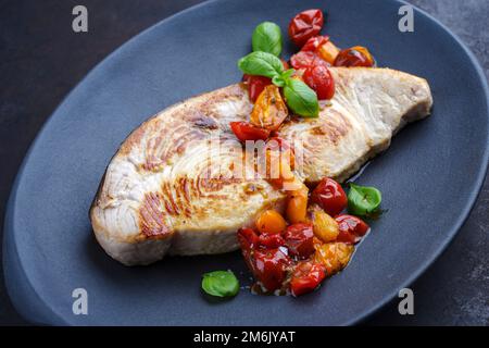 Gebratenes Schwertfischsteak mit Tomaten und Paprika, serviert aus nächster Nähe auf einem Design-Teller Stockfoto