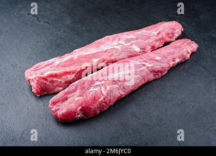 Traditionelle zwei rohe duroc-Schweinefilet-Stücke werden als Nahaufnahme auf einem schwarzen Brett mit Kopierbereich angeboten Stockfoto