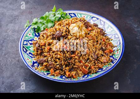 Traditioneller fergana-Plov aus Usbekisch mit Devsira-Reis und Lammfleisch, serviert aus nächster Nähe auf einer handgefertigten laganplatte Stockfoto