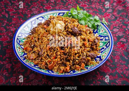 Traditioneller fergana-Plov aus Usbekisch mit Devsira-Reis und Lammfleisch, serviert aus nächster Nähe auf einer handgefertigten laganplatte Stockfoto