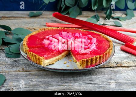 Moderner traditioneller deutscher Rhabarber-Ricotta-Kuchen mit Pudding und Gemüse, serviert aus nächster Nähe auf einer Platte im nordischen Design Stockfoto