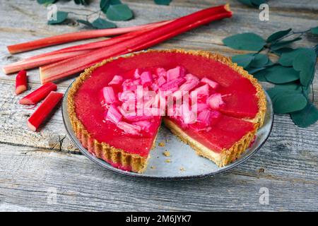 Moderner traditioneller deutscher Rhabarber-Ricotta-Kuchen mit Pudding und Gemüse, serviert aus nächster Nähe auf einer Platte im nordischen Design Stockfoto