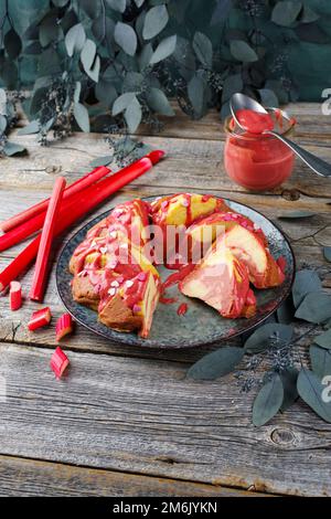 Traditioneller Käsepudding-Kuchen mit Rhabarberquak und Vanillescreme, serviert als Nahaufnahme auf einer Designerplatte mit Cottage-Stil Stockfoto