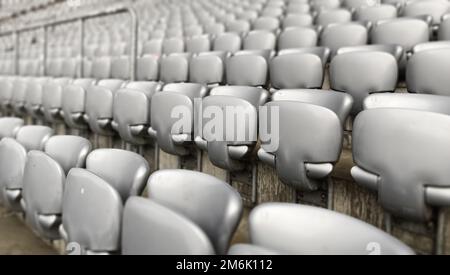 Leere graue Stühle in einem Stadion. Kunststoffsitze in Reihen. Wiederholung und Symmetrie. Stockfoto