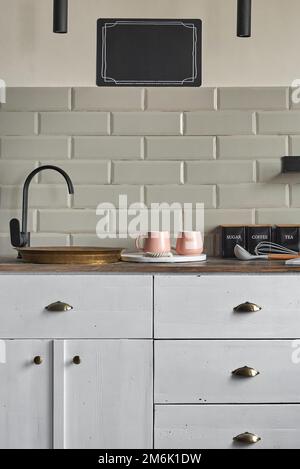Wohnhaus weiße Schränke mit Kupfer-Waschbecken an der Küchentheke. Stockfoto