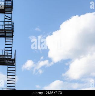 Silhouette einer Feuerflucht auf einem Hochhaus vor blauem Himmel Stockfoto