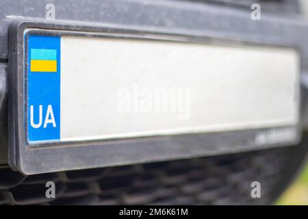 Ukrainisches Nummernschild ohne Zahlen und Buchstaben auf der Nahaufnahme der Stoßstange. Staatsbürgerschaftssymbol und gelbblaue Flagge. Ungewöhnlich Stockfoto