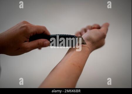 Eine depressive Frau versuchte Selbstmord, indem sie ihre Handgelenkvenen mit einem Messer durchtrennte. Stockfoto